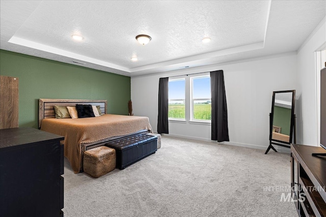 carpeted bedroom featuring a textured ceiling, a raised ceiling, and baseboards