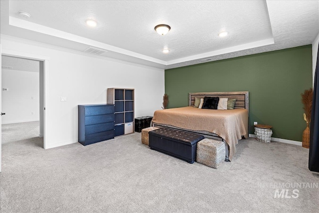 carpeted bedroom with a raised ceiling, baseboards, visible vents, and a textured ceiling