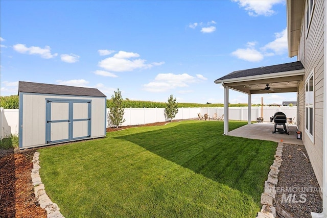 view of yard with a storage shed, a fenced backyard, an outdoor structure, a ceiling fan, and a patio