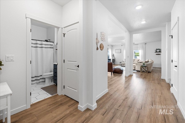 hallway featuring baseboards and light wood finished floors