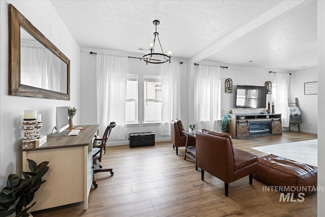 living room featuring an inviting chandelier, wood finished floors, baseboards, and a textured ceiling