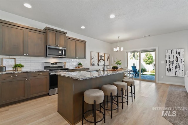 2252 E Tiger Lily Dr, Boise, ID 83716 - kitchen with stainless steel appliances, a chandelier, light wood finished floors, light stone countertops, and backsplash