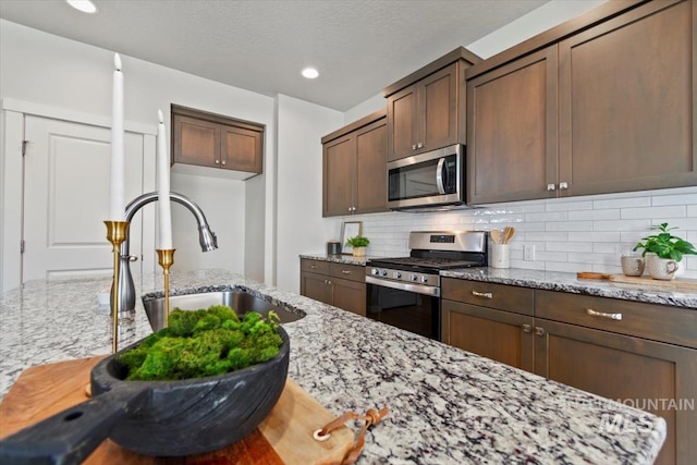 2252 E Tiger Lily Dr, Boise, ID 83716 - kitchen with appliances with stainless steel finishes, a sink, light stone counters, backsplash, and recessed lighting