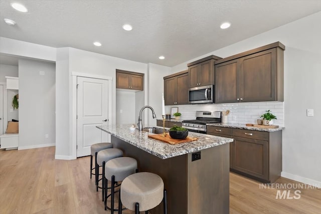 2252 E Tiger Lily Dr, Boise, ID 83716 - kitchen featuring appliances with stainless steel finishes, a sink, light wood-style floors, light stone counters, and recessed lighting