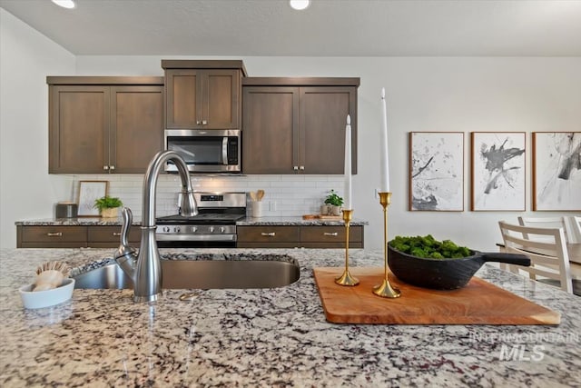 2252 E Tiger Lily Dr, Boise, ID 83716 - kitchen with stainless steel appliances, light stone counters, tasteful backsplash, dark brown cabinets, and a sink
