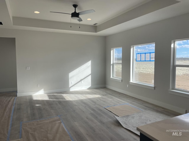 unfurnished room with ceiling fan, baseboards, a tray ceiling, recessed lighting, and wood finished floors