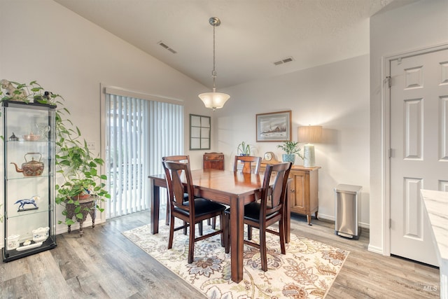 dining space featuring lofted ceiling, light wood-style floors, and baseboards