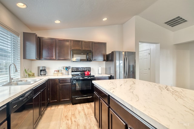kitchen featuring black appliances, vaulted ceiling, a sink, light wood-style floors, and dark brown cabinets