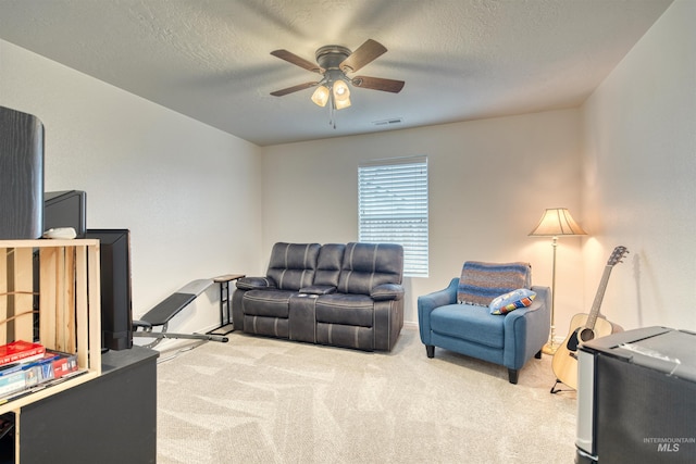 living area featuring carpet floors, a ceiling fan, a textured ceiling, and baseboards