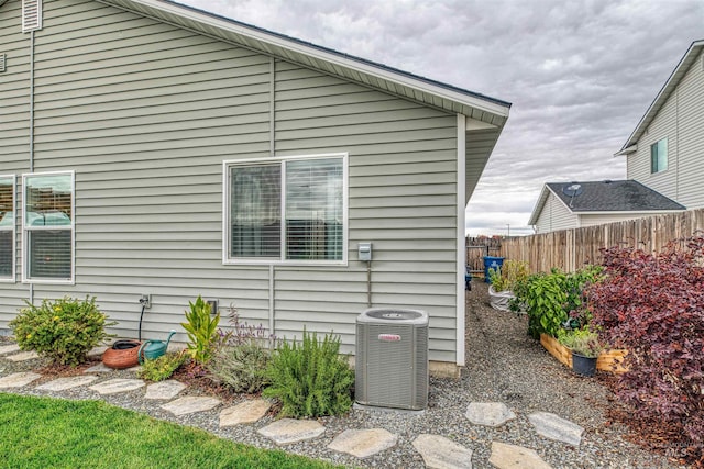 view of property exterior with central AC and fence