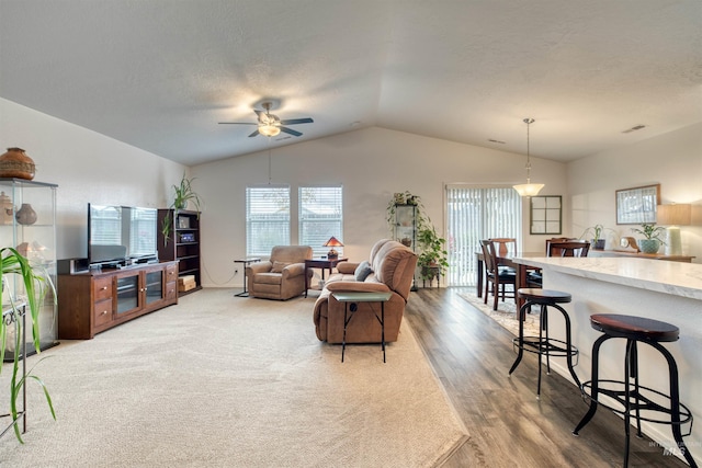 living area with vaulted ceiling, wood finished floors, and a ceiling fan