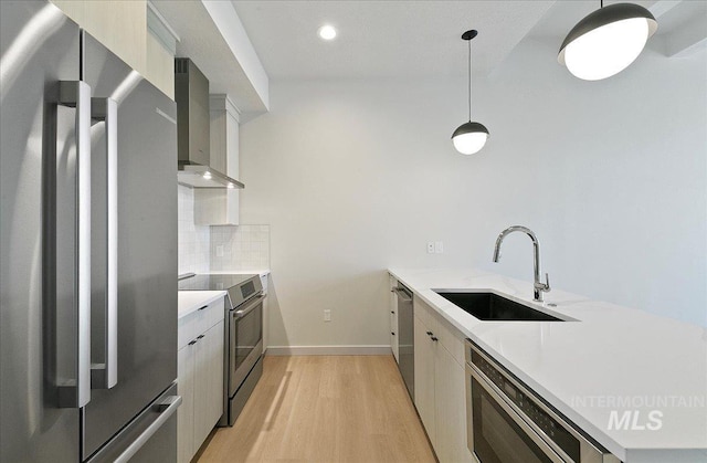 4340 E Haystack St Unit 304, Boise, ID 83716 - kitchen featuring appliances with stainless steel finishes, a sink, wall chimney exhaust hood, light wood-style flooring, and backsplash