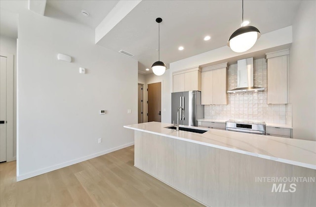 4340 E Haystack St Unit 304, Boise, ID 83716 - kitchen featuring wall chimney range hood, appliances with stainless steel finishes, tasteful backsplash, light wood-type flooring, and a sink