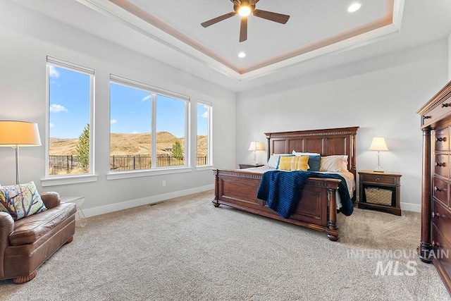 bedroom featuring light carpet, a mountain view, a raised ceiling, and ceiling fan