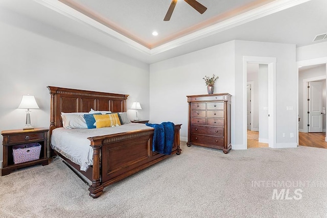 bedroom with crown molding, light colored carpet, a raised ceiling, and ceiling fan