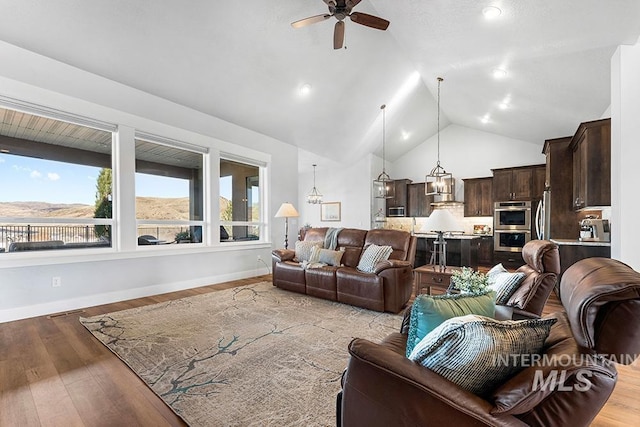 living room featuring ceiling fan, a mountain view, high vaulted ceiling, and light hardwood / wood-style flooring