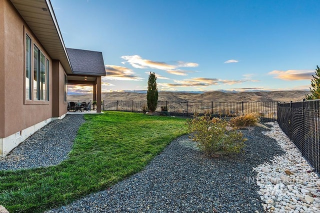 yard at dusk featuring a mountain view and a patio area