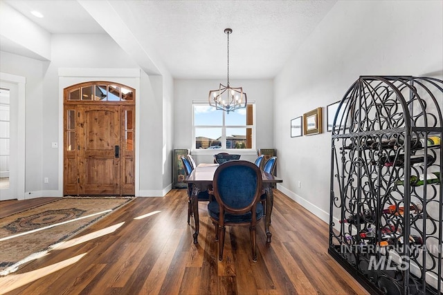 dining area featuring dark hardwood / wood-style floors, a notable chandelier, and a textured ceiling