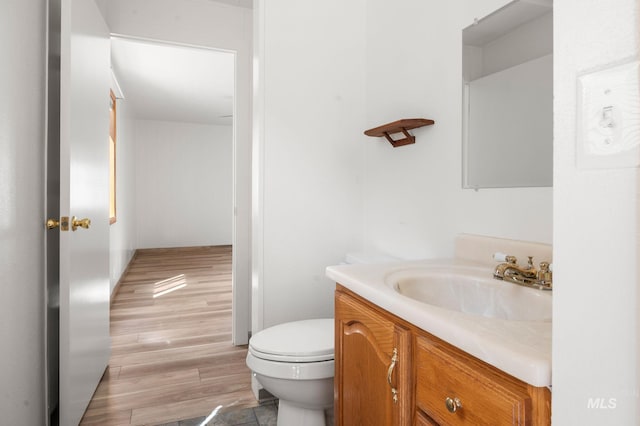 bathroom with toilet, wood finished floors, and vanity
