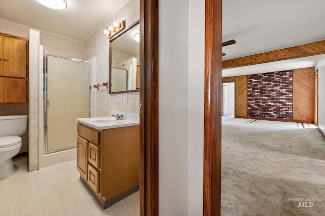 bathroom with toilet, wood walls, a shower stall, vanity, and ornamental molding
