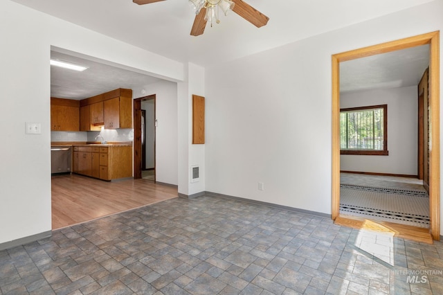 unfurnished living room with ceiling fan, baseboards, stone finish floor, and visible vents