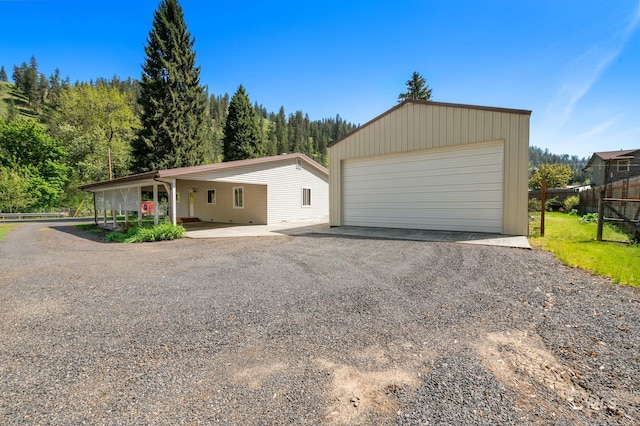 view of front of house with fence, a garage, and an outbuilding