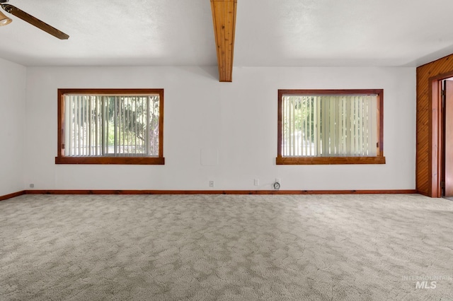 carpeted spare room with beamed ceiling, a ceiling fan, and baseboards