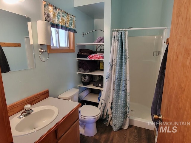 bathroom featuring a stall shower, vanity, toilet, and wood finished floors