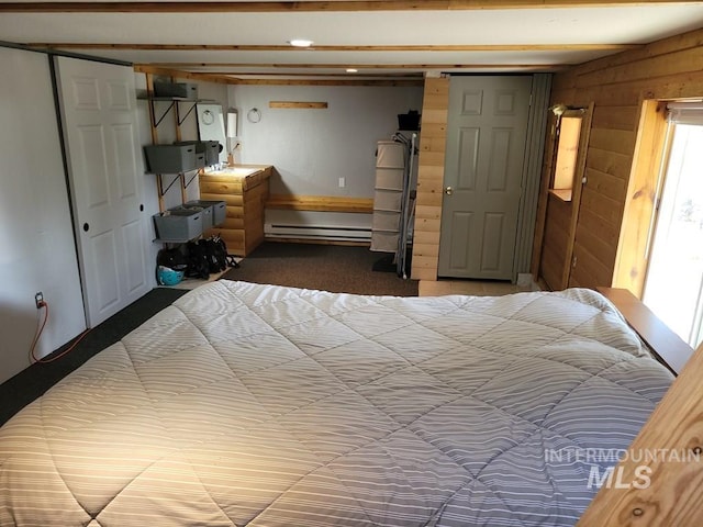 bedroom with a baseboard radiator, wooden walls, carpet flooring, and a closet