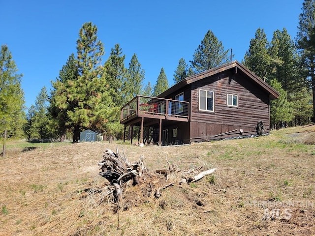 rear view of house featuring an outdoor structure, a wooden deck, and a storage unit