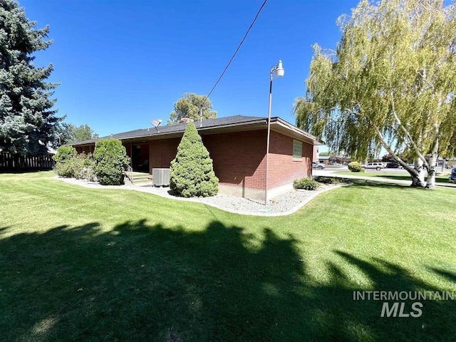 rear view of property featuring cooling unit and a lawn