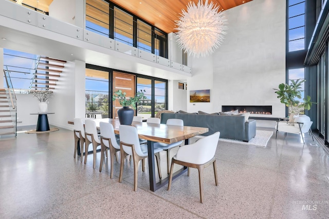 dining room featuring a towering ceiling, a large fireplace, and a chandelier