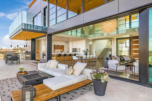 view of terrace with an outdoor living space with a fire pit and a balcony