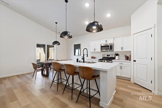 19321 Geneva Way, Caldwell, ID 83605 - kitchen featuring stainless steel appliances, a sink, light wood-type flooring, a center island with sink, and a breakfast bar area