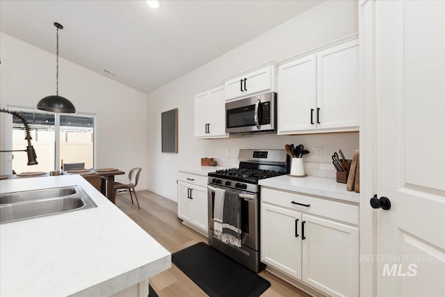 19321 Geneva Way, Caldwell, ID 83605 - kitchen with lofted ceiling, white cabinetry, light wood-style floors, and appliances with stainless steel finishes