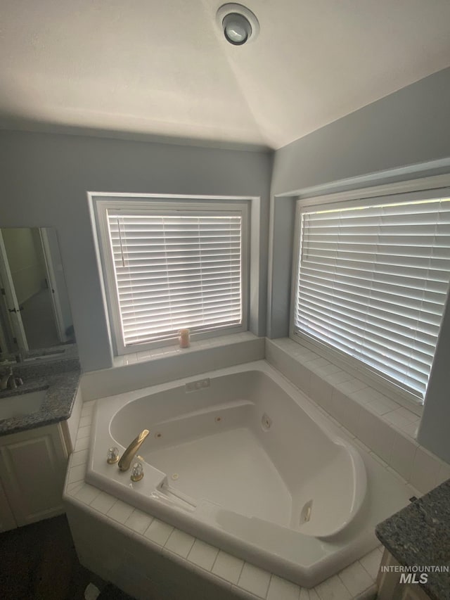 bathroom with a tub with jets and vanity