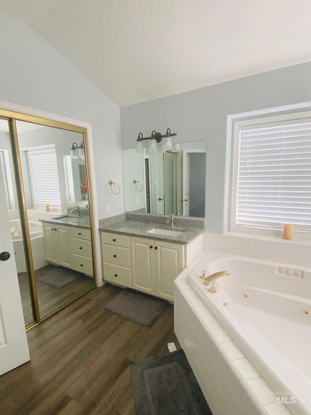 full bath featuring vanity, a whirlpool tub, lofted ceiling, and wood finished floors