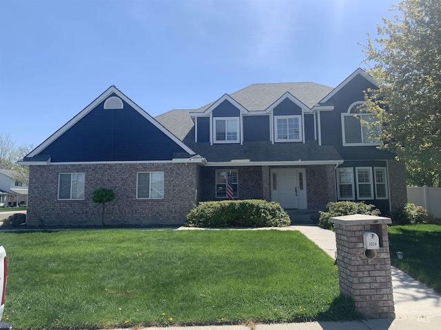 view of front of home featuring a front yard, brick siding, and a shingled roof