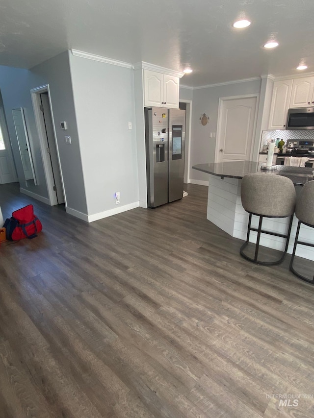 kitchen featuring dark countertops, white cabinetry, stainless steel appliances, and crown molding