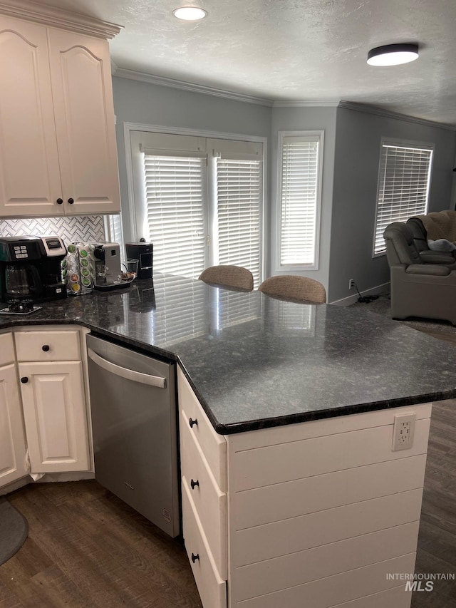 kitchen with a peninsula, white cabinets, crown molding, stainless steel dishwasher, and dark wood-type flooring