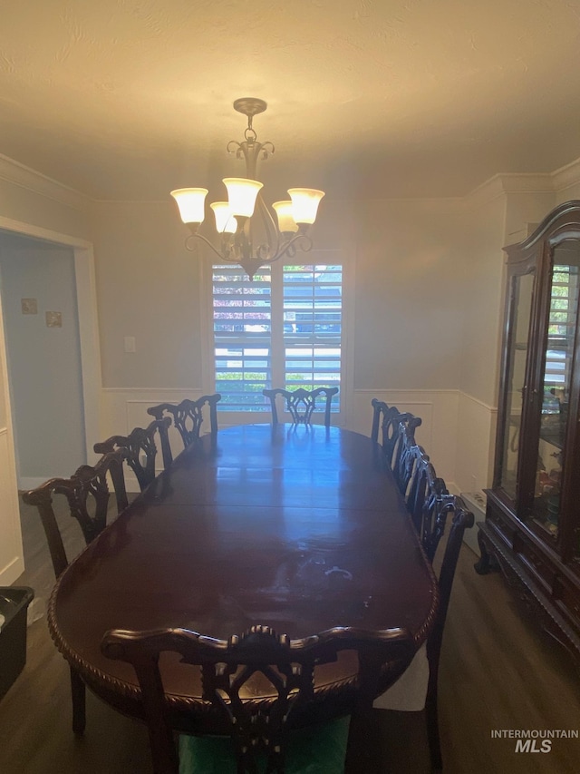 dining area with a decorative wall, crown molding, wainscoting, and a chandelier
