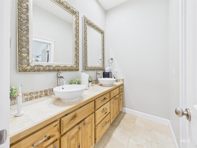 bathroom with double vanity, tile patterned floors, and baseboards