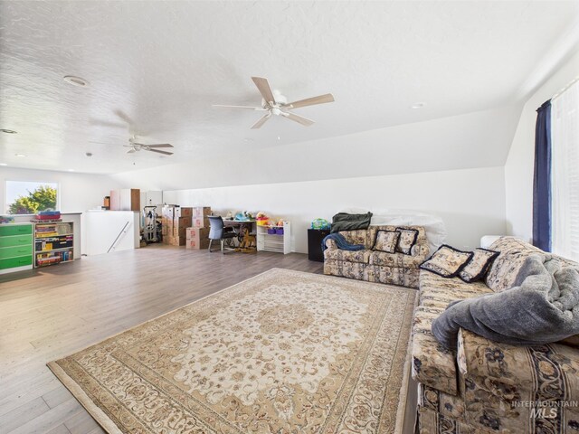living area with wood finished floors, a ceiling fan, and lofted ceiling