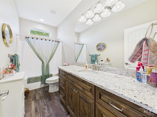 bathroom featuring toilet, wood finished floors, vanity, and shower / bath combo