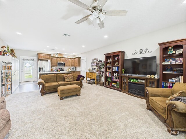 living room with recessed lighting, ceiling fan, a fireplace, and light carpet