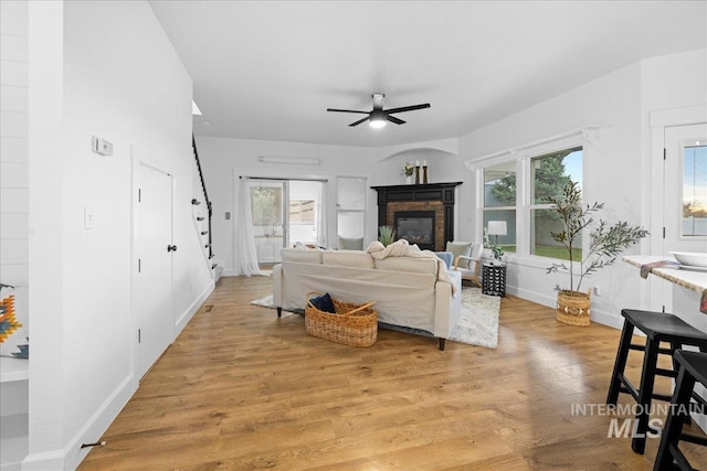 living room with ceiling fan, plenty of natural light, and light wood-type flooring