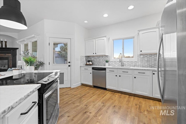 kitchen with a wealth of natural light, sink, stainless steel appliances, light hardwood / wood-style flooring, and white cabinets