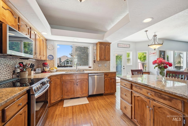 1229 N Hiltonhead Way, Eagle, ID 83616 - kitchen featuring appliances with stainless steel finishes, a sink, light wood-style flooring, decorative backsplash, and brown cabinets