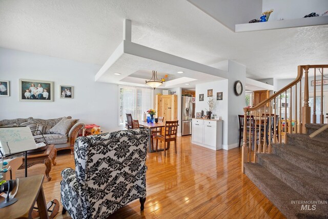 1229 N Hiltonhead Way, Eagle, ID 83616 - living area featuring stairs, light wood-style flooring, a textured ceiling, and baseboards