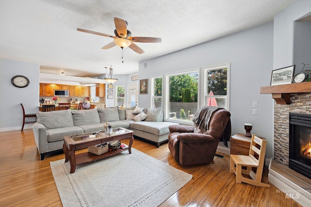 1229 N Hiltonhead Way, Eagle, ID 83616 - living area with a fireplace, ceiling fan, light wood-style floors, and baseboards